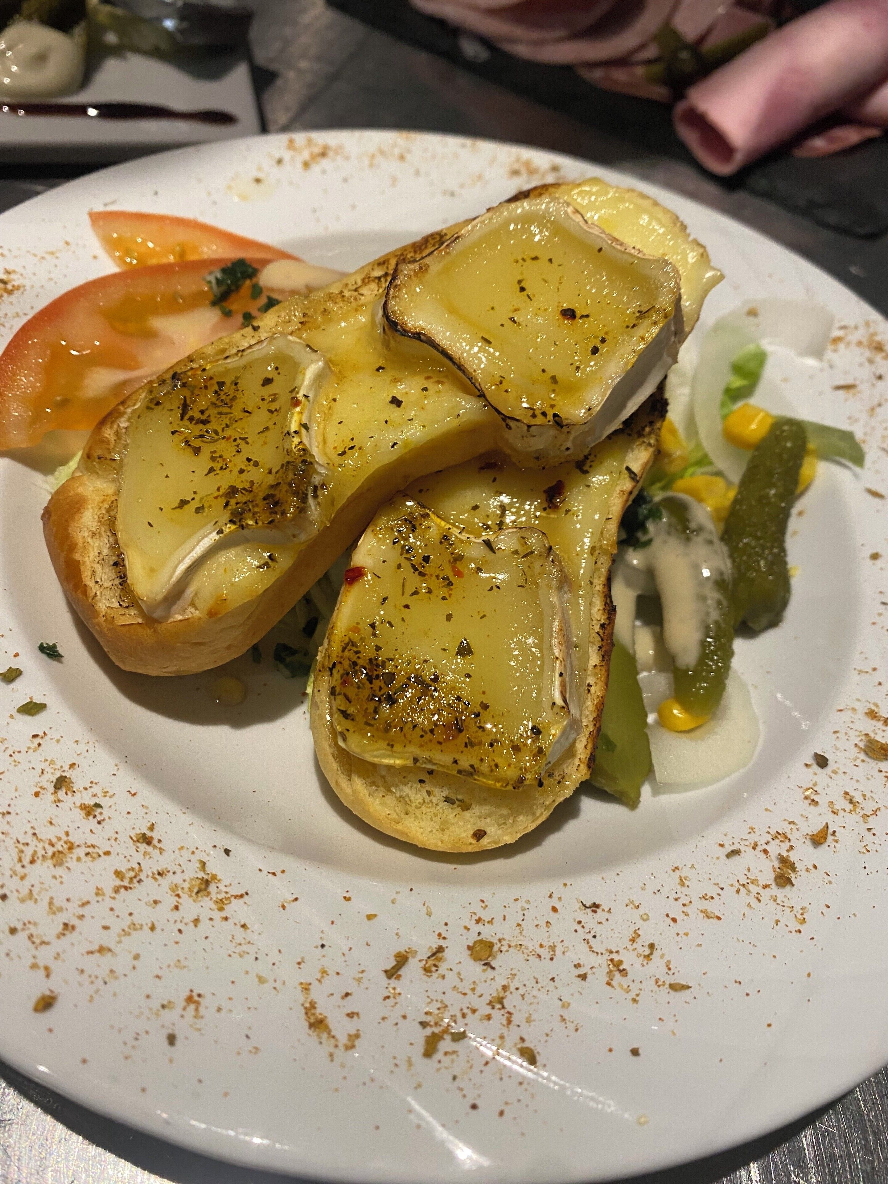 A plate with grilled cheese sandwiches, a slice of tomato, and a side salad.