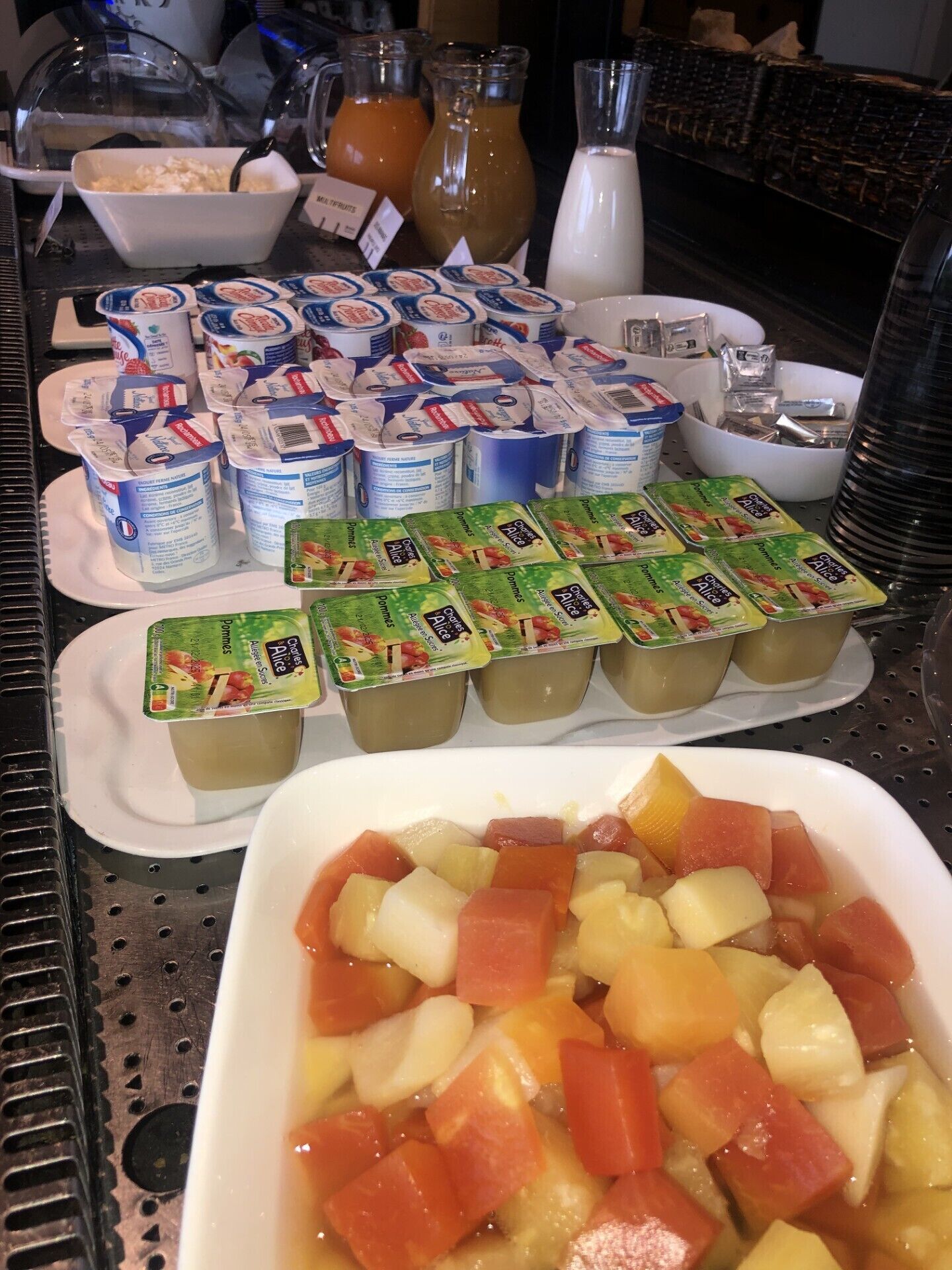 Una mesa de buffet con diversos alimentos, incluyendo yogur, fruta y salsas.