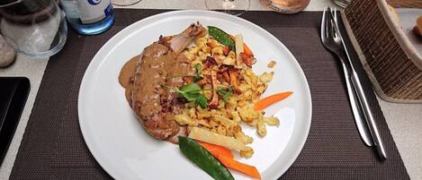 Un plato de comida con carne, verduras y salsa.