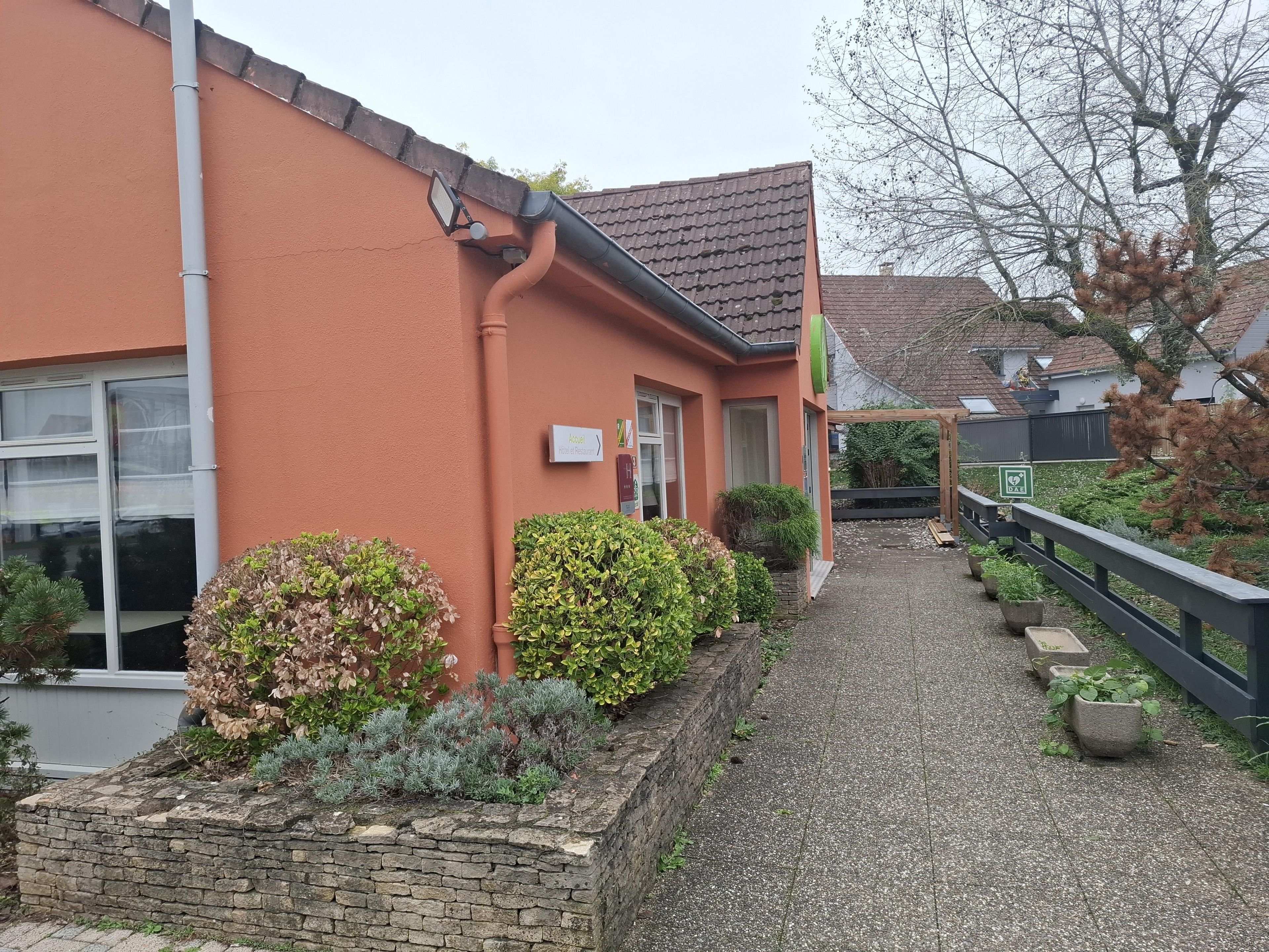 A building with a red exterior, a paved pathway, and a wooden fence.