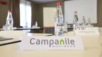 A conference room with tables, water bottles, and name cards labeled "Campanile Business".