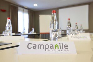 Un salón de conferencias con mesas, botellas de agua y tarjetas de identificación con la etiqueta "Campanile Business".
