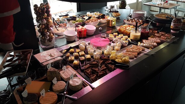 A buffet with various cheeses, desserts, and beverages.
