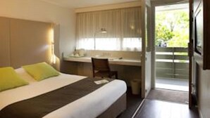 A hotel room with a bed, a desk, and a window with curtains.