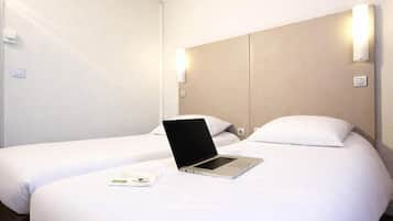 A hotel room with two beds, a laptop on one bed, and wall-mounted lights.