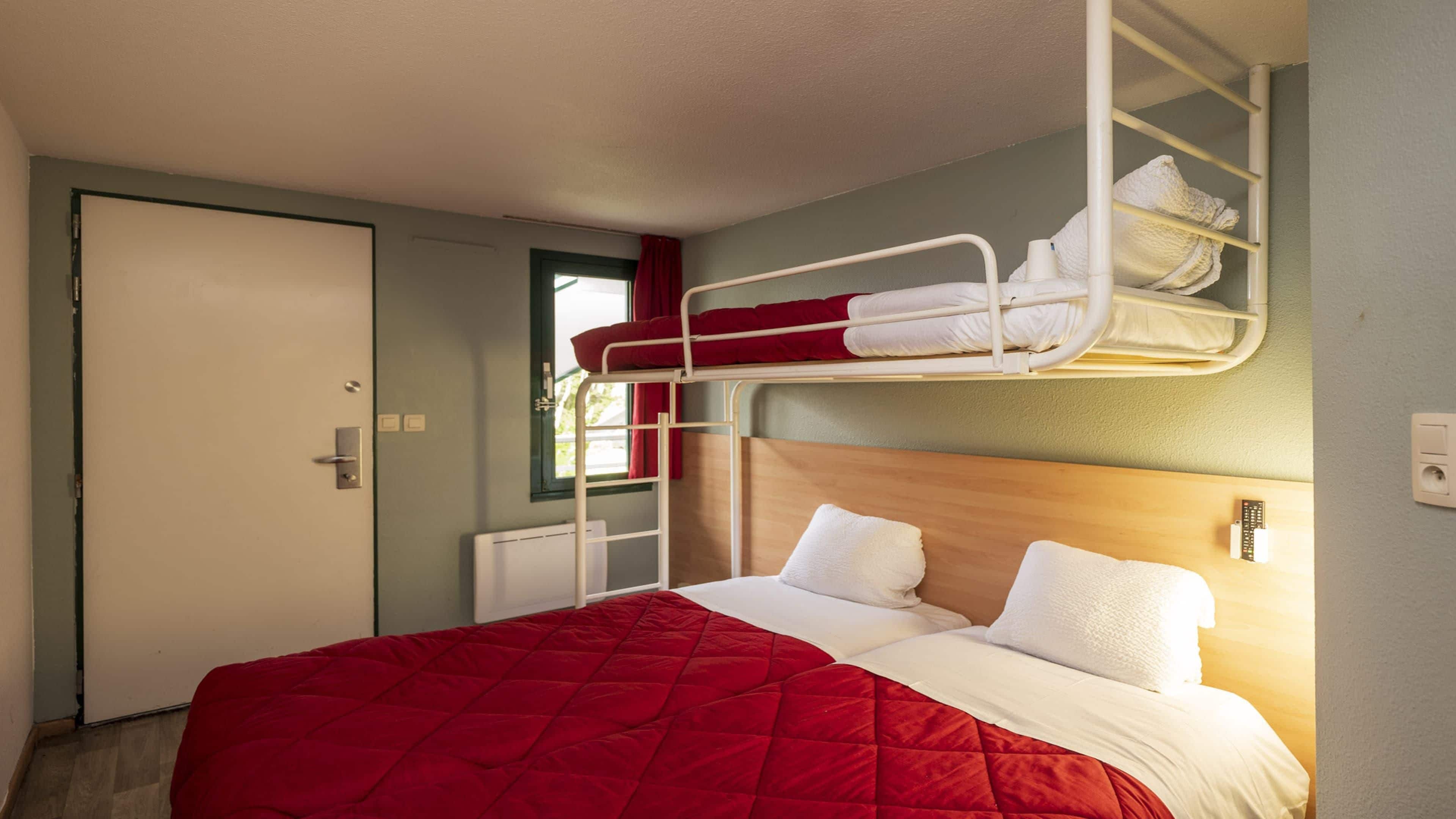 A room with a bunk bed, a single bed, and a door.