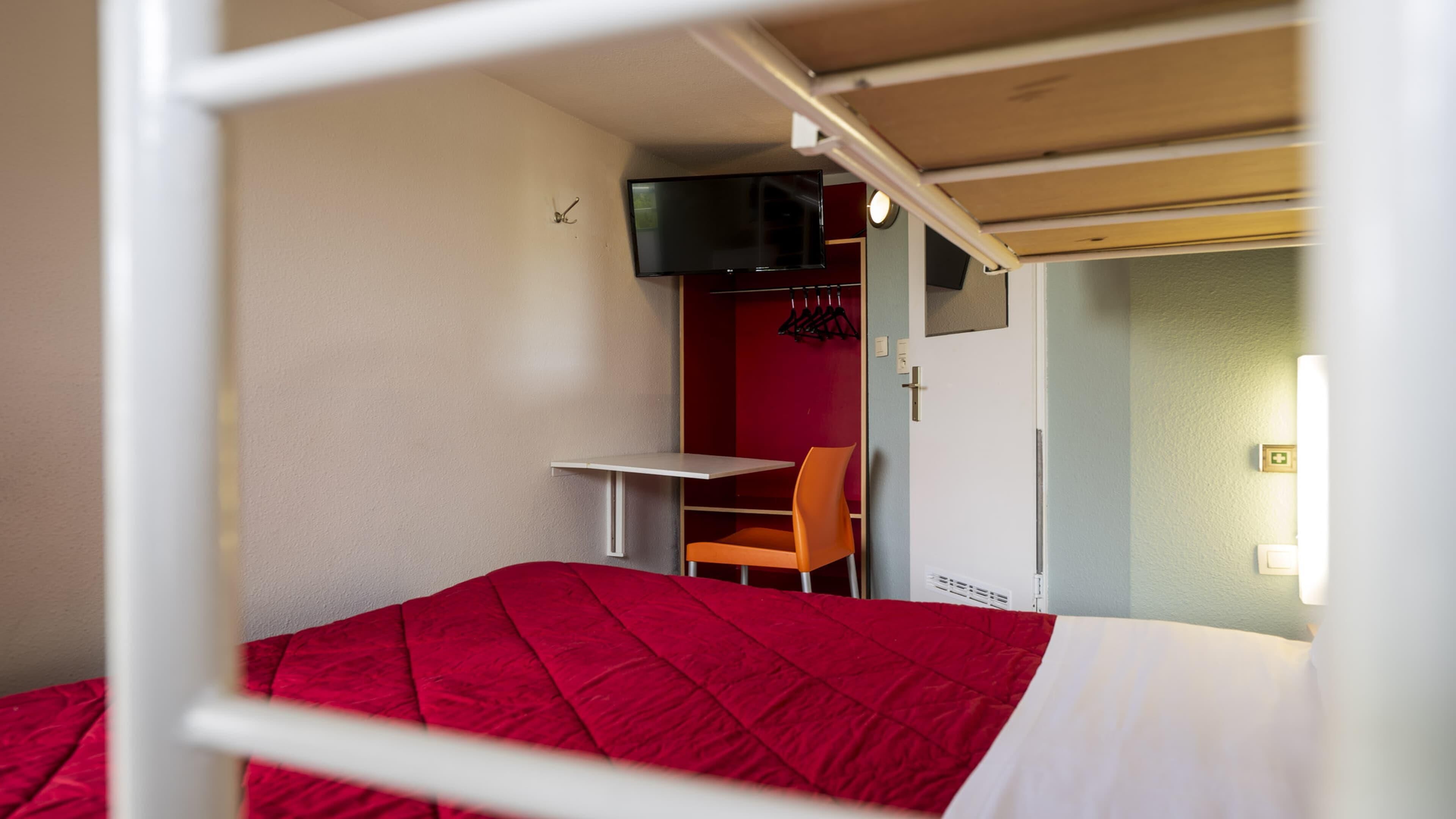 A bedroom with a bed, a desk, and a chair.