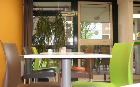 A dining area with a white table and chairs, a potted plant, and a view of the outdoors.