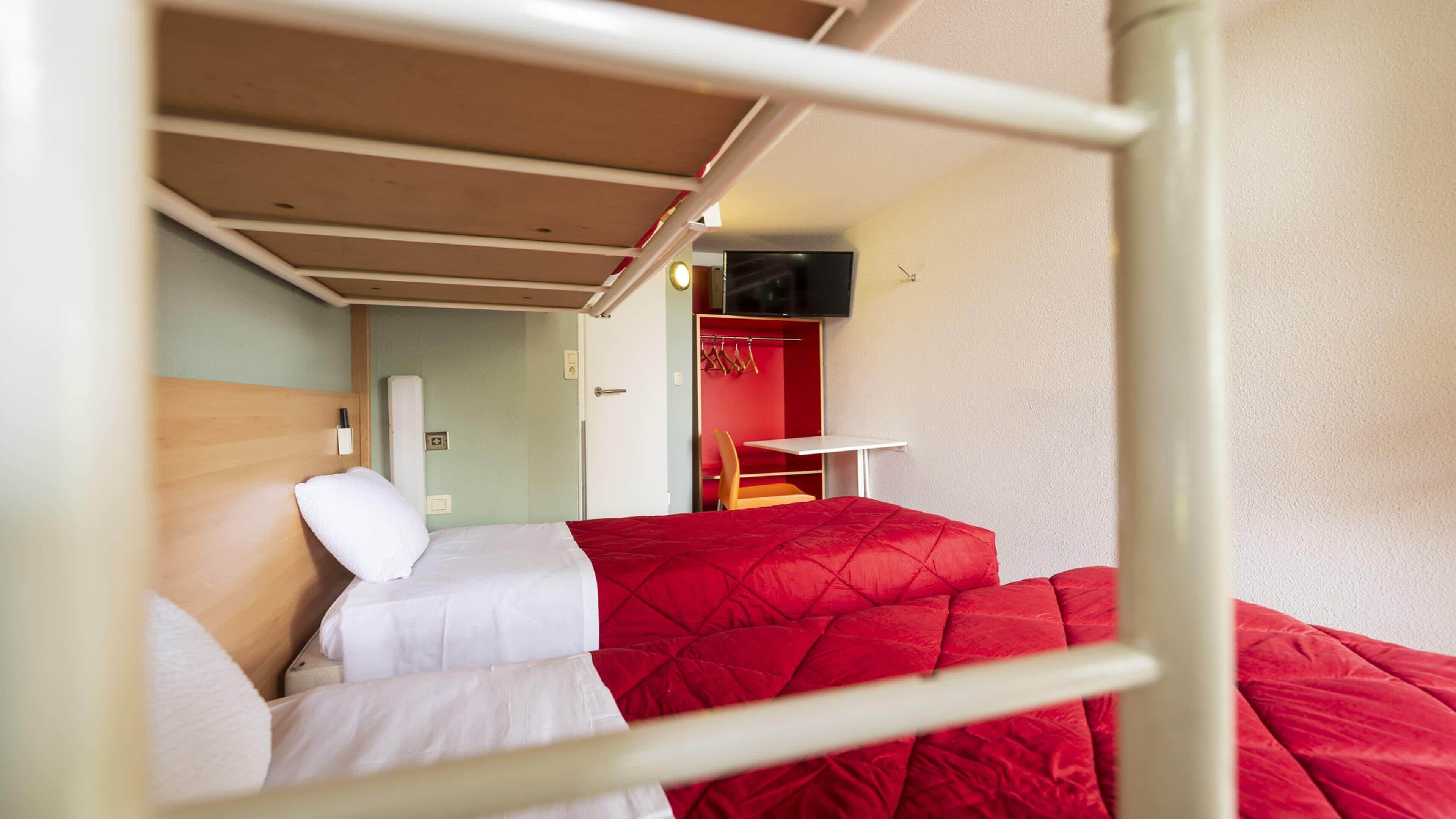 Une chambre avec des lits superposés, un bureau et un téléviseur.