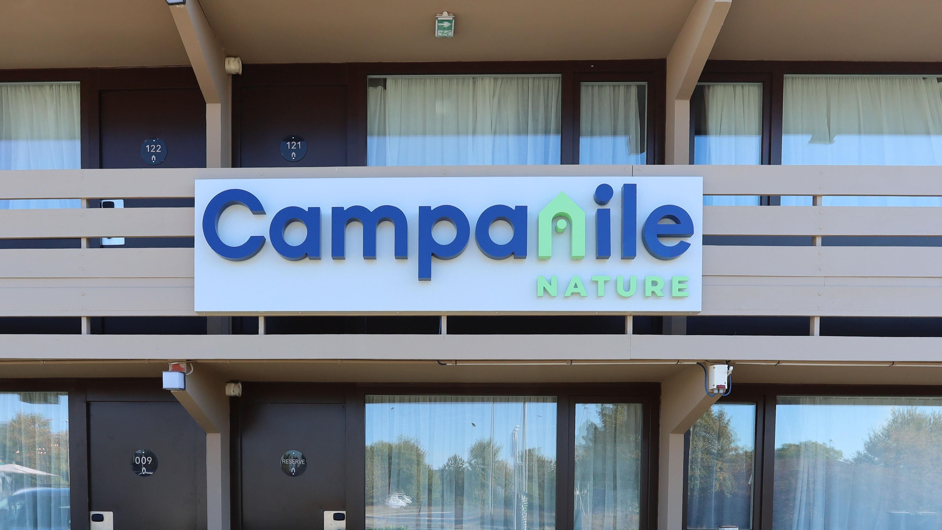 Un letrero de hotel con el nombre 'Campanile Nature' y los números de habitación 121 y 122 a la vista.