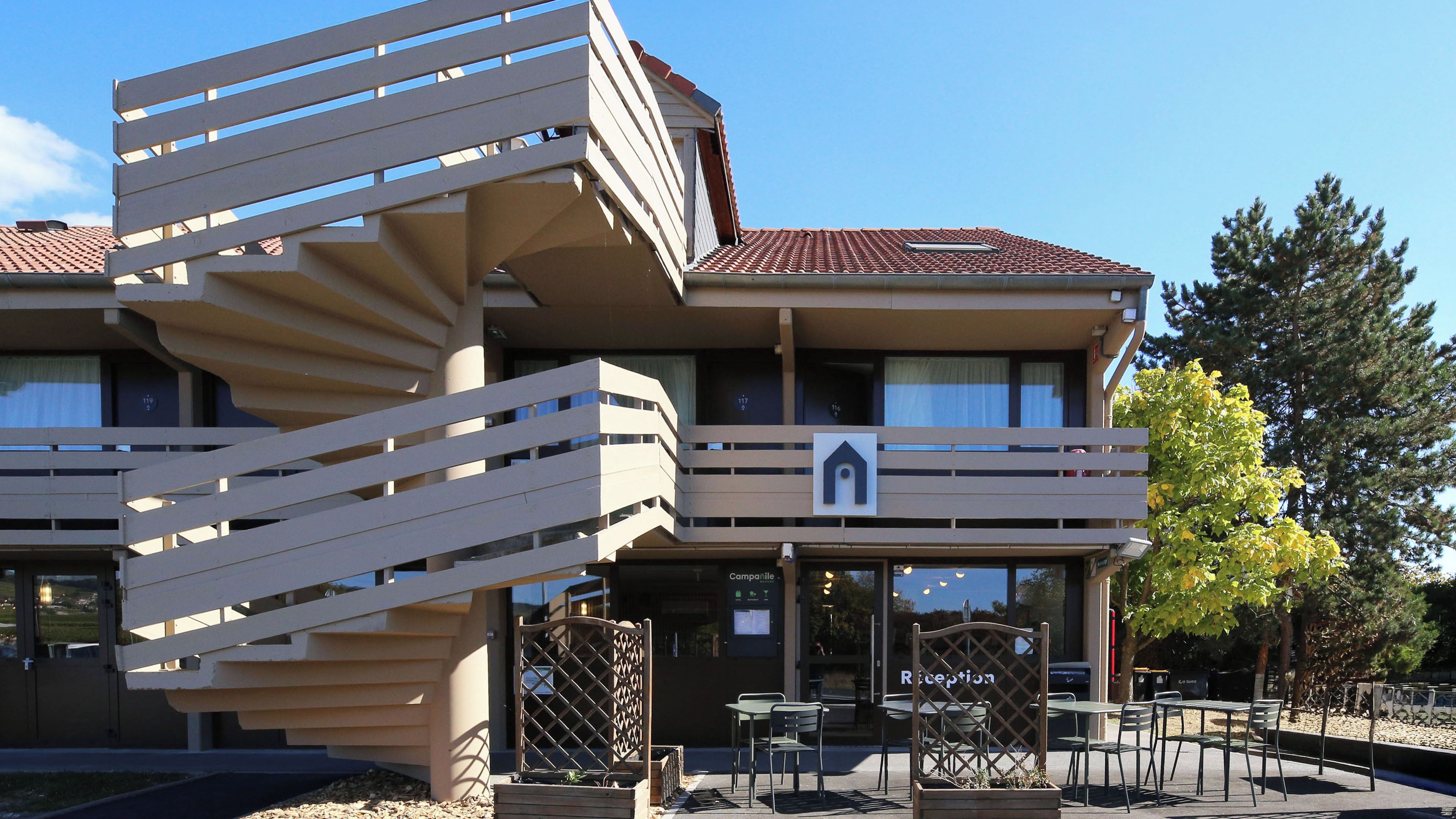 Un edificio de varios pisos con una escalera espiral, zona de estar al aire libre y una recepción.