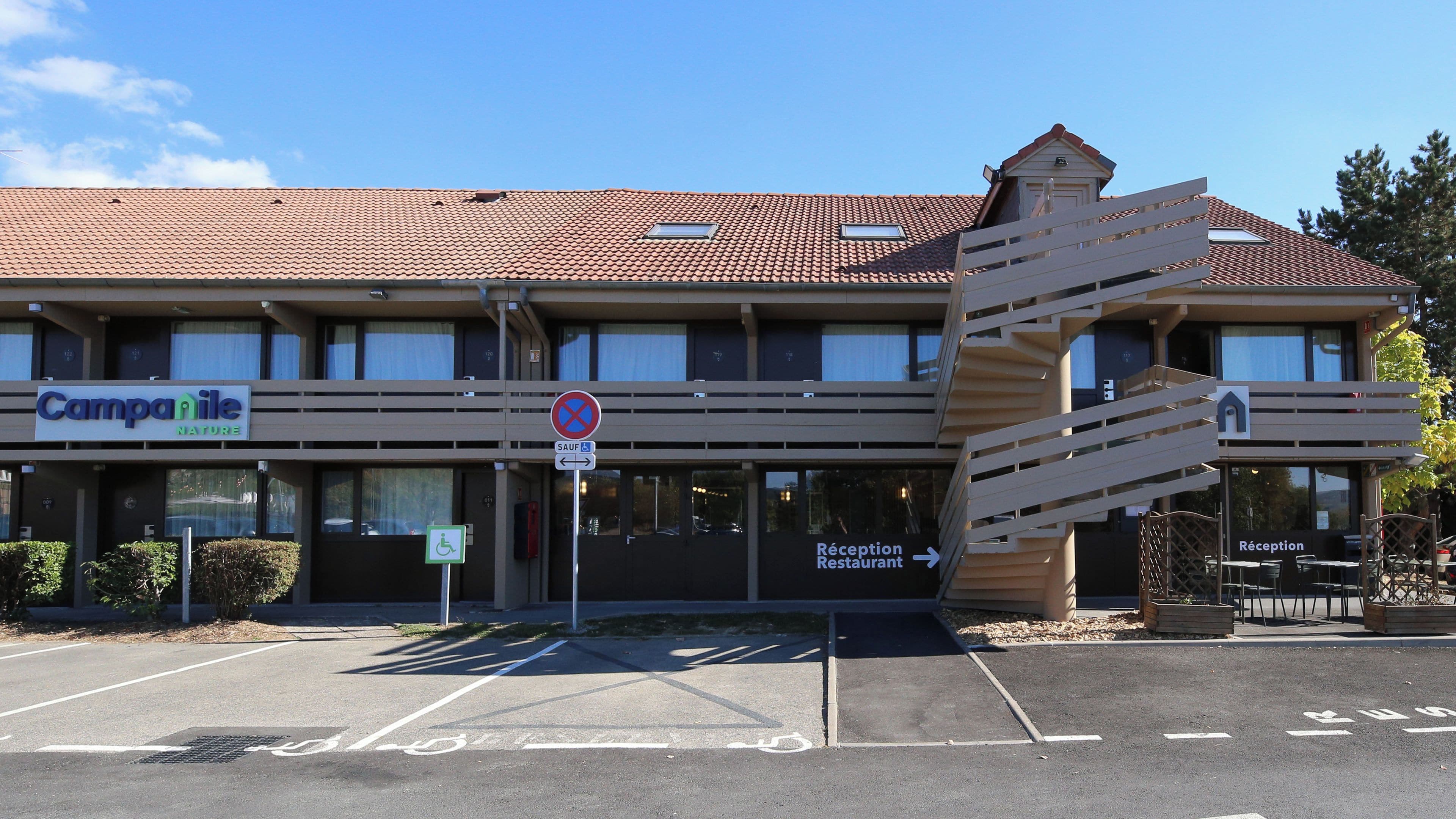 A hotel with a ramp entrance, a reception desk, and a sign indicating a restaurant.