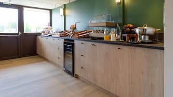 A kitchen with a dishwasher, a fruit bowl, and a coffee station.