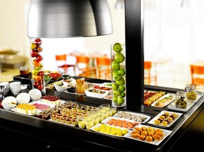 Un bufé con diversos alimentos y una composición decorativa de manzanas.
