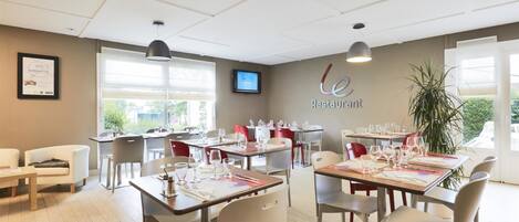 A restaurant with tables set for dining, a TV on the wall, and a sign that reads "Restaurant."