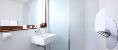 A modern bathroom with a white sink, a mirror with a wooden frame, and a glass shower enclosure.