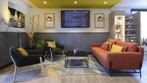 A modern living room with a sofa, armchairs, a coffee table, and a TV mounted on the wall. - Campanile NATURE - Bollène (Bollene)