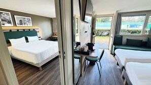 A hotel room with a bed, a desk with a chair, a sofa, and a window with a view of greenery. - Campanile NATURE - Bollène (Bollene)
