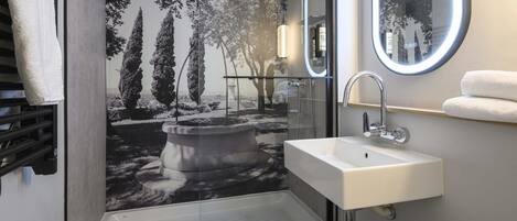 A bathroom with a sink, mirror, and shower.