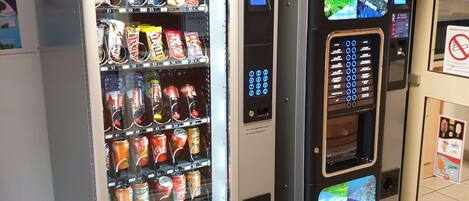 A vending machine with snacks and drinks, a payment terminal, and a digital display.