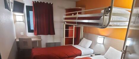 A compact room with two beds, a desk, and a chair.