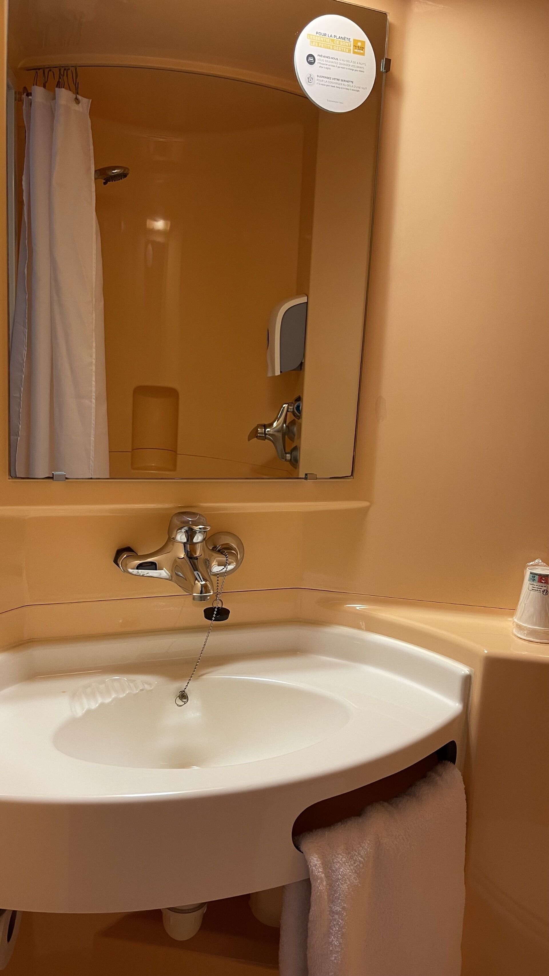 Un baño con lavamanos blanco, un espejo y una cortina de ducha.