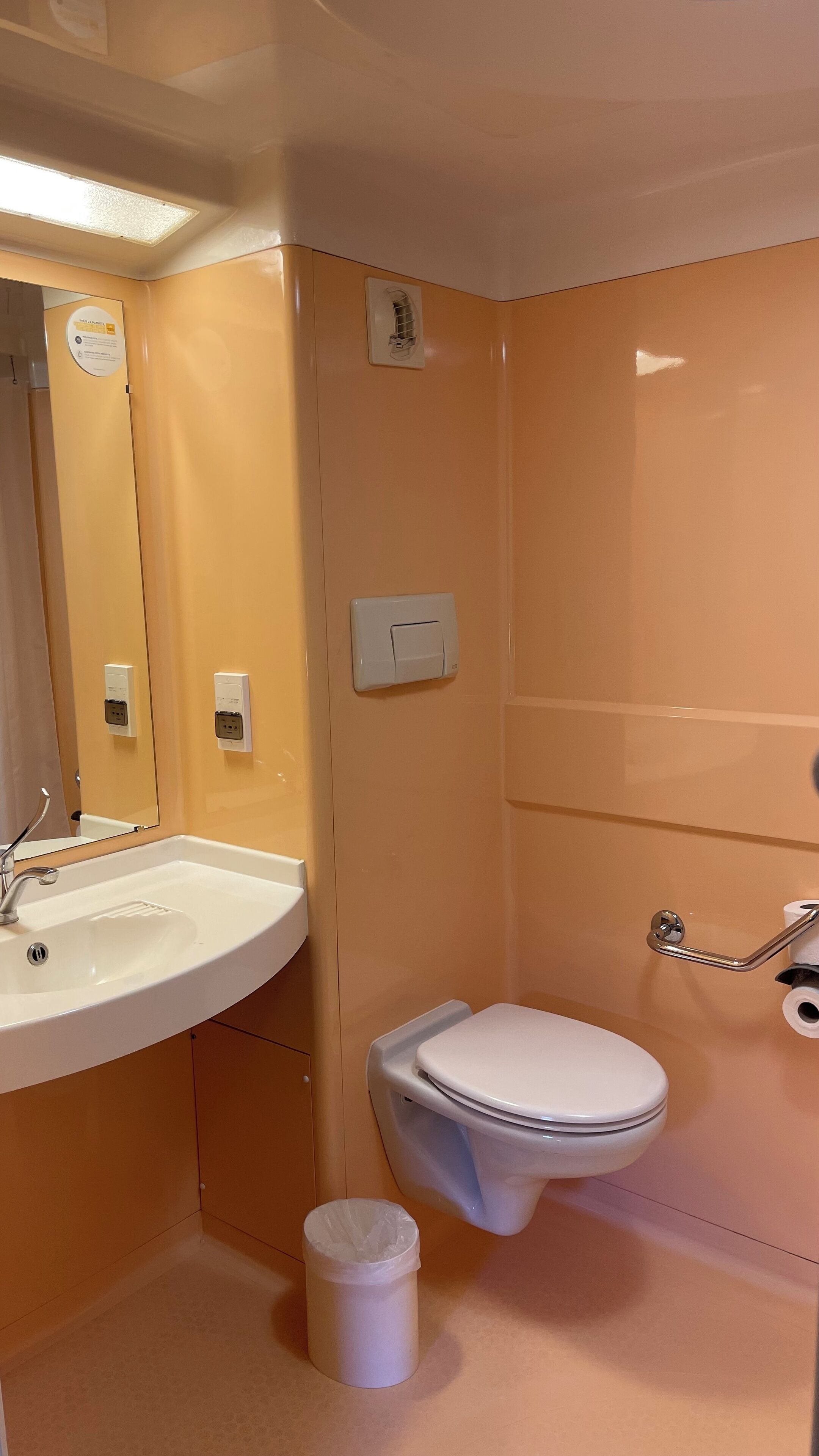 A bathroom with a white sink, a toilet, and a trash can.
