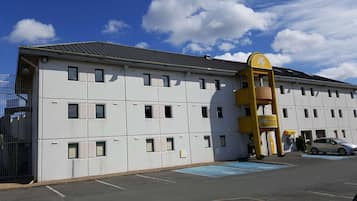 Hotel features a modern design with a flat roof and rectangular windows, offering wheelchair accessibility and a gated entrance.