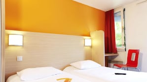 Habitación de hotel con dos camas, una silla roja y una ventana con cortinas.