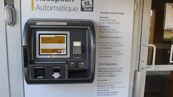 Ein automatisierter Empfangsbereich mit einem Self-Service-Terminal, einem Empfangsschalter und einem Schild mit den Öffnungszeiten und Informationen zum Frühstück.