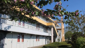 Un hotel de varios pisos con un diseño moderno, con balcones y una escalera central.