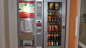 Máquina expendedora con dispensador de bebidas y zona de venta de aperitivos.