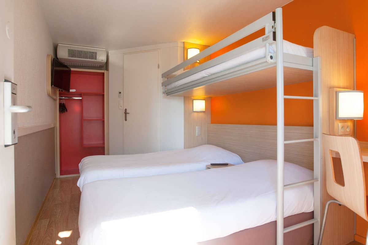 Habitación con literas, un armario y un escritorio.