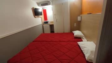 Ein Hotelzimmer mit zwei Betten, einem Fernseher, einer Mikrowelle und einem kleinen Kühlschrank.