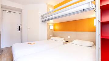 Habitación de hotel con literas, una mesita de noche y una lámpara fijada a la pared.