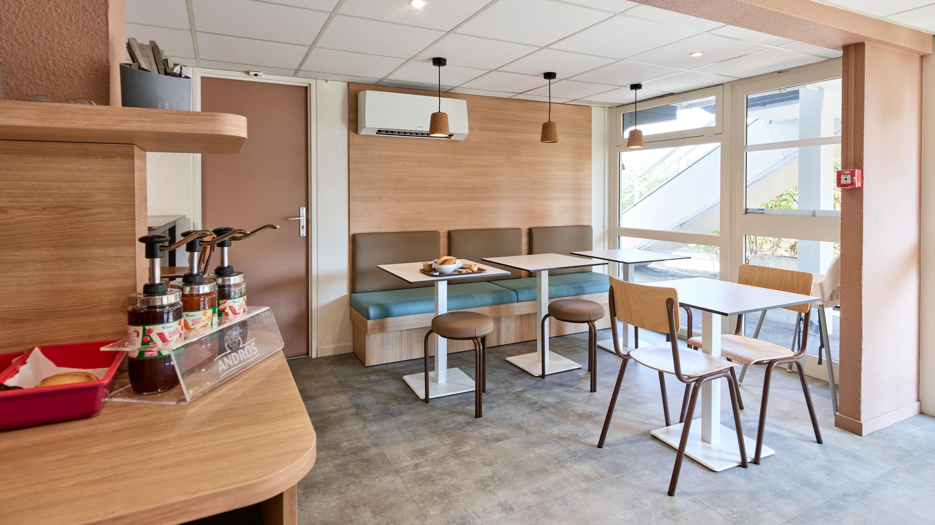 Ein Café mit Holztresen, Sitzbereich und großen Fenstern.