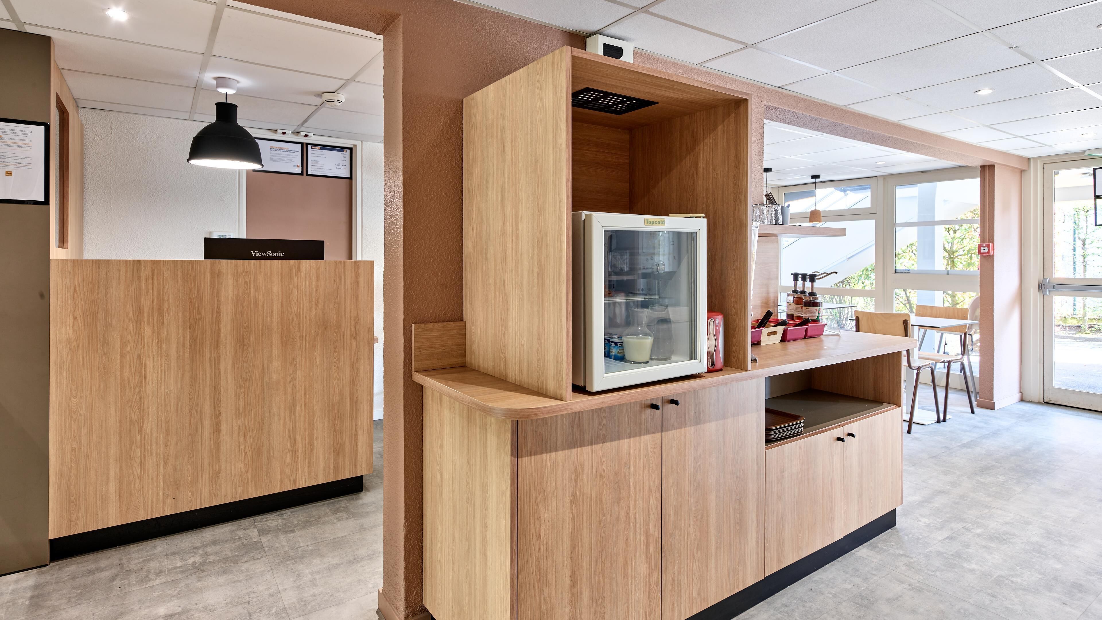 Un interior moderno con armarios de madera, refrigerador y una zona de estar con vistas.