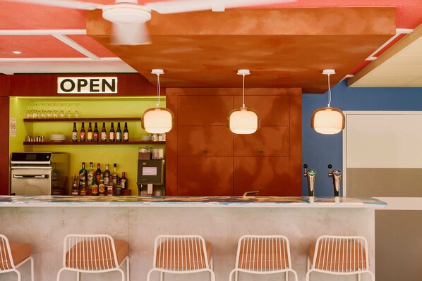 A bar area with a 'OPEN' sign, bar stools, a shelf with bottles, and a counter with taps. - greet Hotel Versailles - Voisins Le Bretonneux (Voisins-le-Bretonneux)