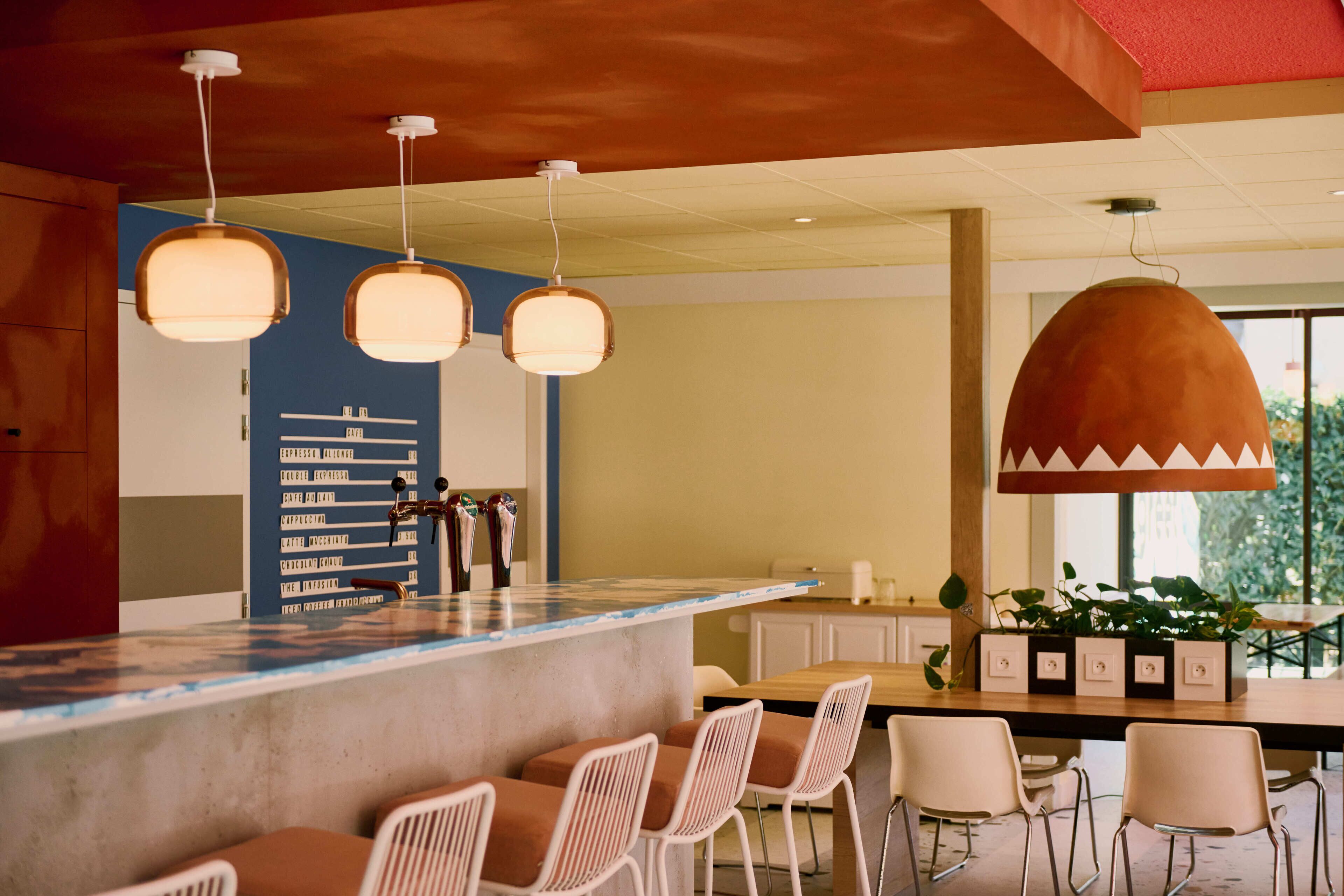 A bar area with a concrete counter, white bar stools, and pendant lighting.