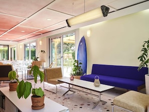 A modern indoor space with a blue sofa, a table, and potted plants. - greet Hotel Versailles - Voisins Le Bretonneux (Voisins-le-Bretonneux)