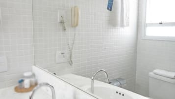 A bathroom with white tiled walls, a white sink, and a shower.