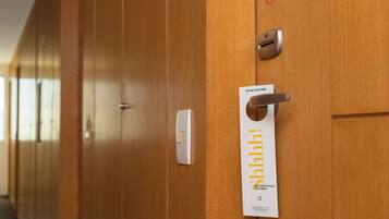 A hotel room door with a 'Do Not Disturb' sign and a 'Recharging Battery' sign.