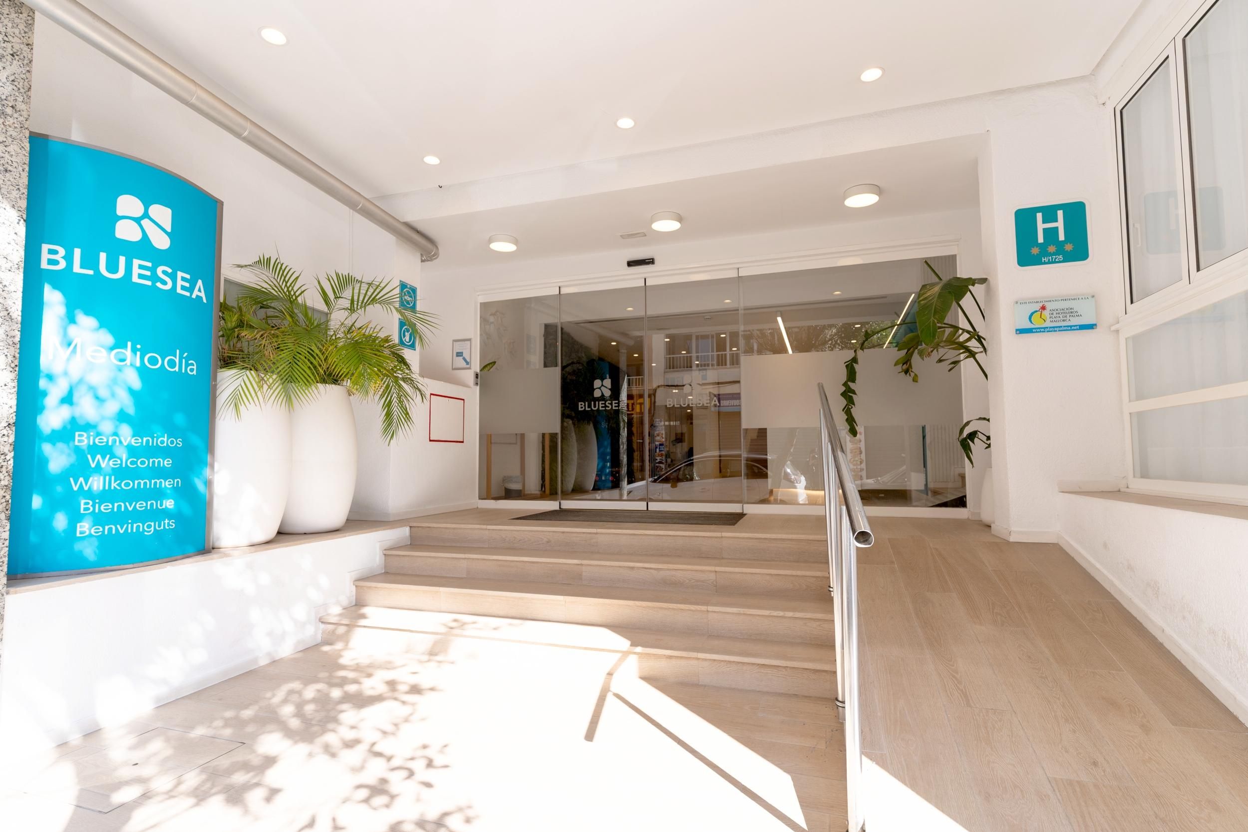 Un vestíbulo de hotel con un mostrador de recepción, una escalera y plantas en macetas.