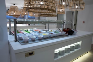 A buffet setup with various food containers and a glass display case. - BLUESEA Mediodia (Llucmajor)