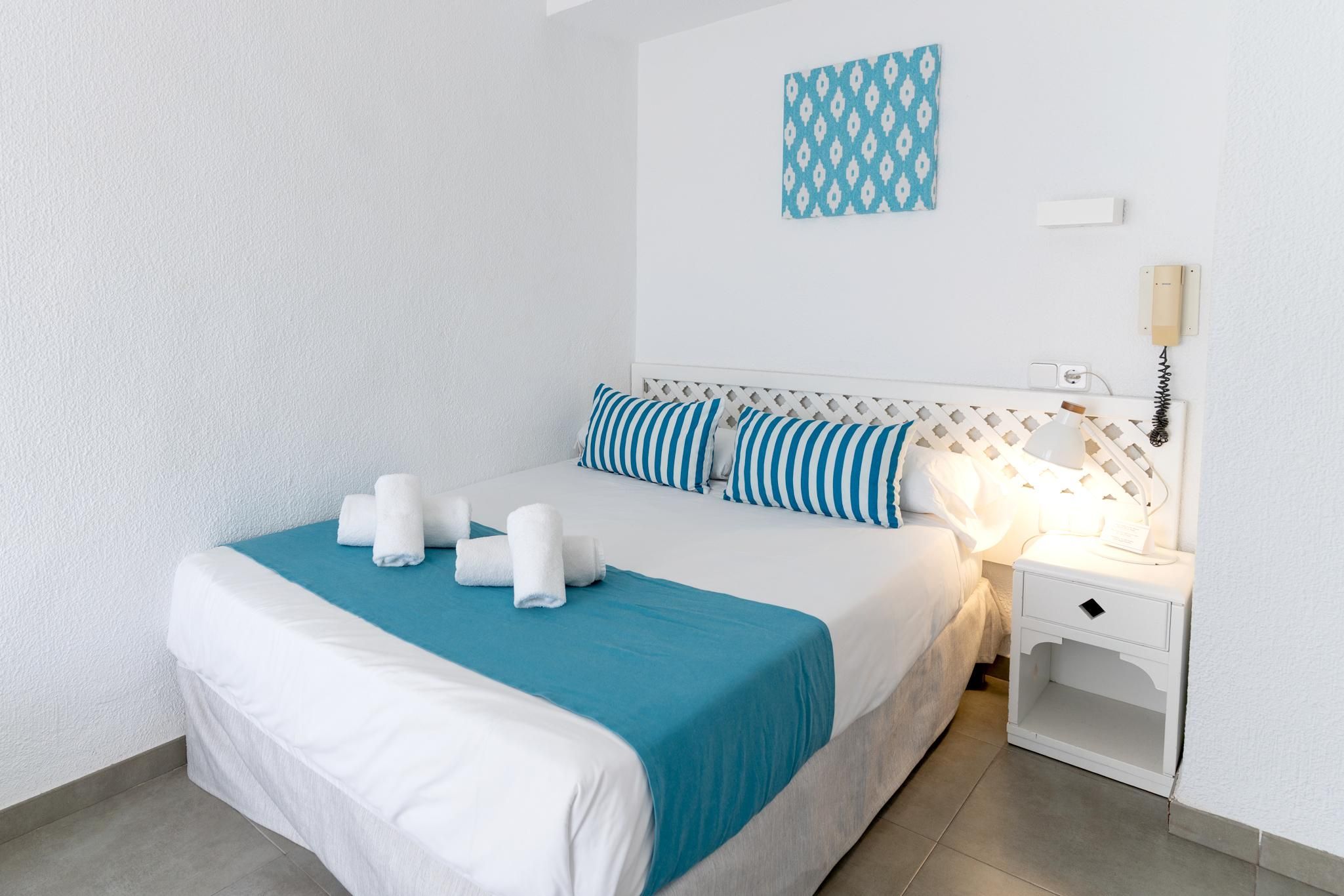 Une chambre d’hôtel avec un lit, une table de chevet, une lampe et un téléphone.