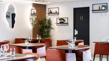 Un interior de restaurante moderno con mesas y sillas, una puerta negra y estanterías con adornos.