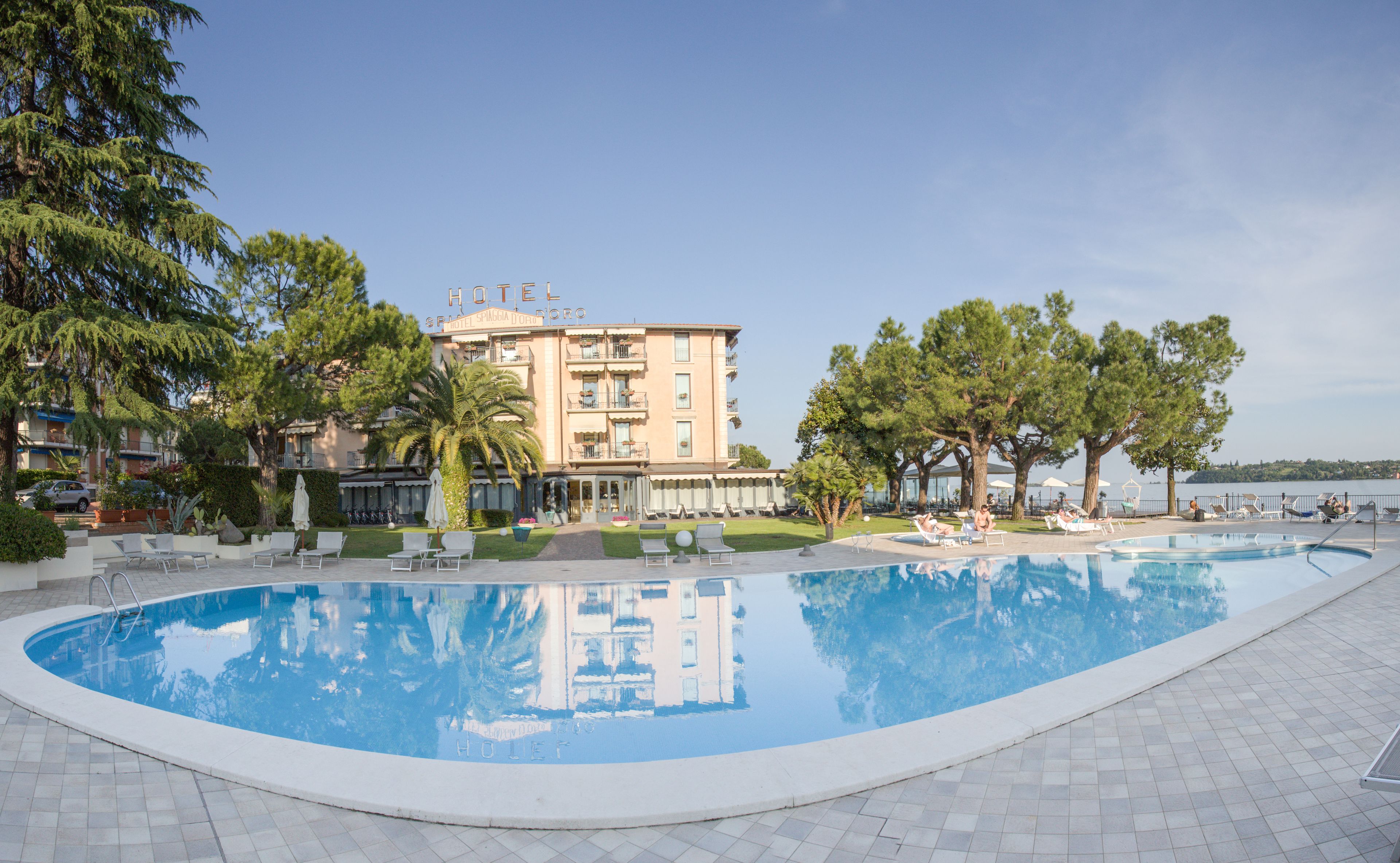A hotel with a swimming pool, lounge chairs, and a view of the sea.