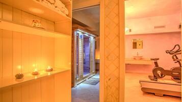 Un área de spa con sauna, camilla de masaje y cinta de correr.