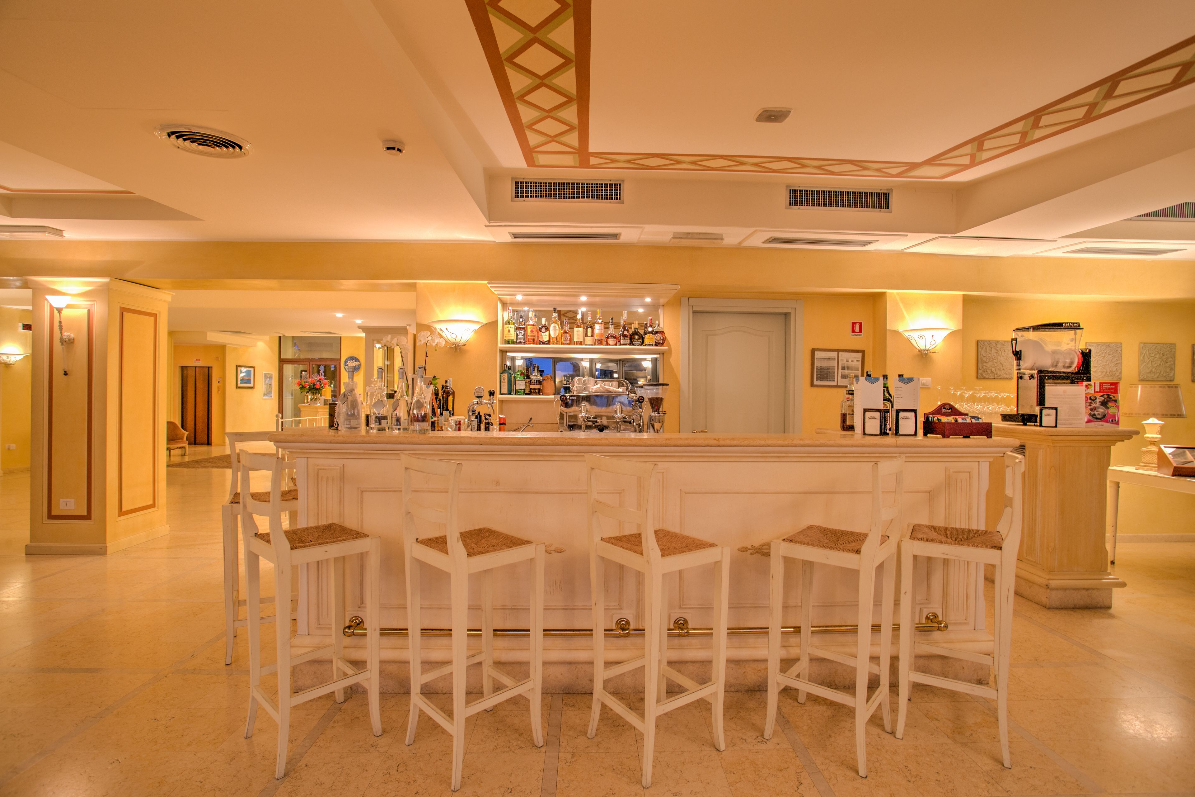 Zona de bar con mostrador, taburetes y ambiente luminoso.