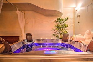 Un jacuzzi con panel de control, una planta en maceta y un perchero para toallas.